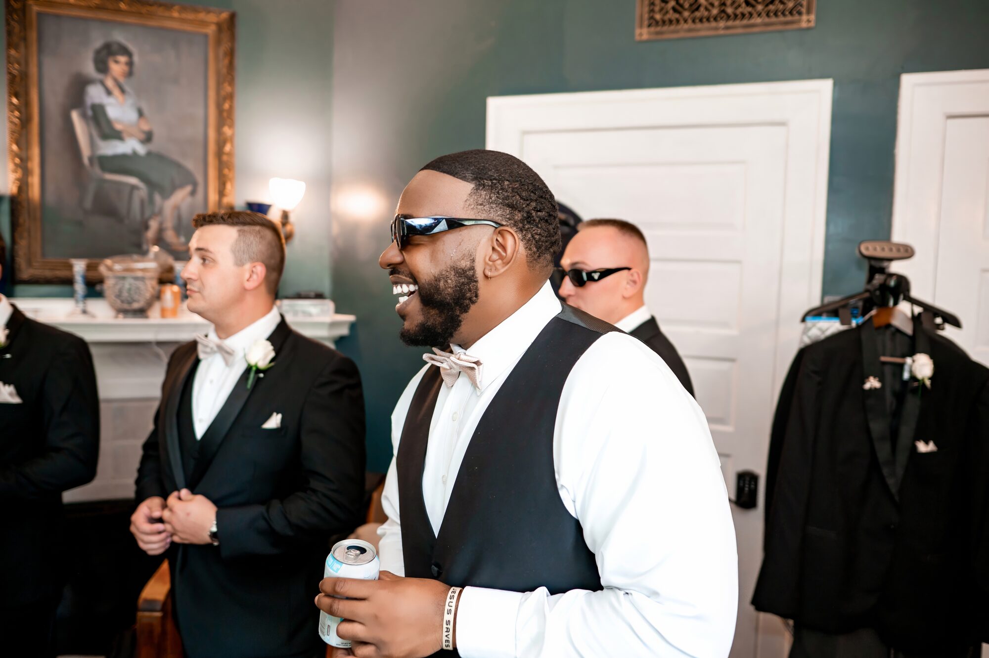 Groom laughs with his groomsmen while getting ready at Sydonie Mansion