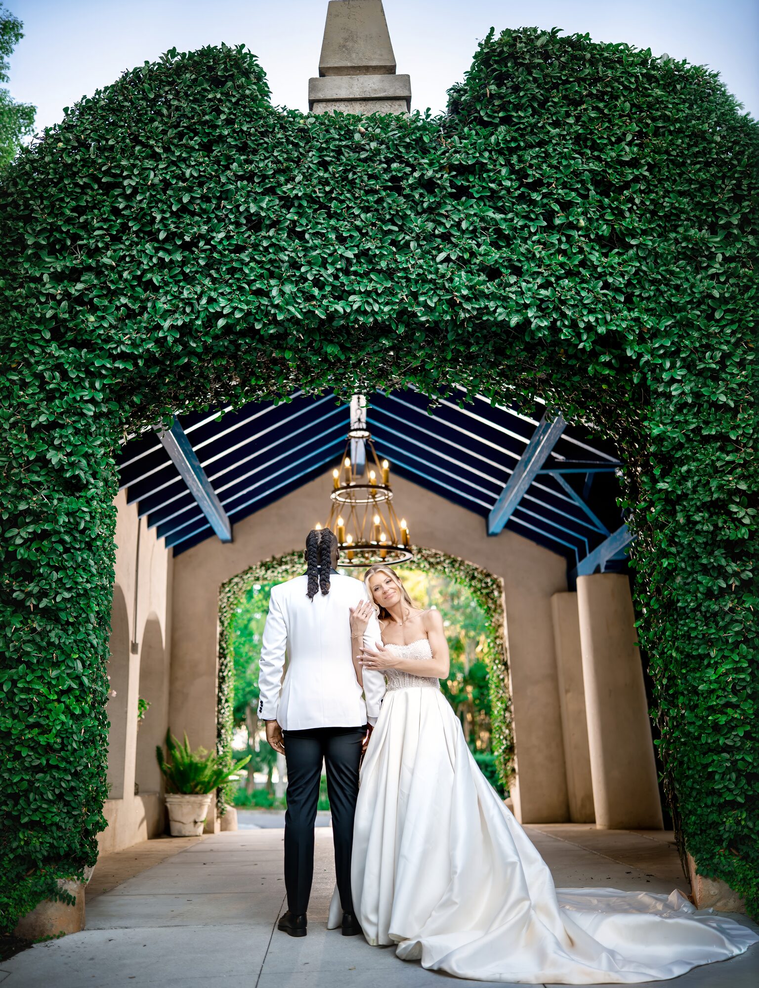 Bride and groom embrace in the chandelier-lit hedge tunnel at Sydonie Mansion