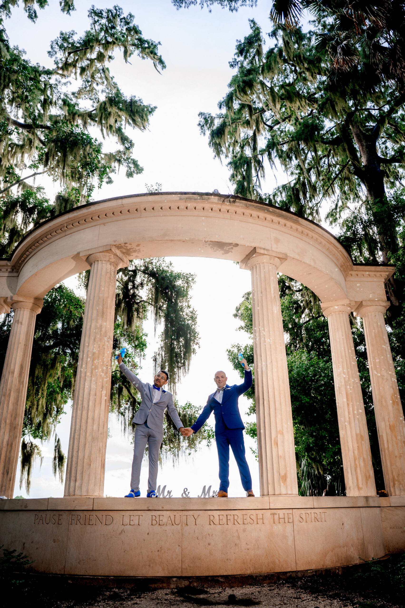 Ben and Leo hold hands on the rotunda ledge framed by cypress at Kraft Azalea Garden